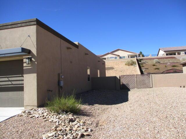 view of side of home featuring a garage, fence, a gate, and stucco siding