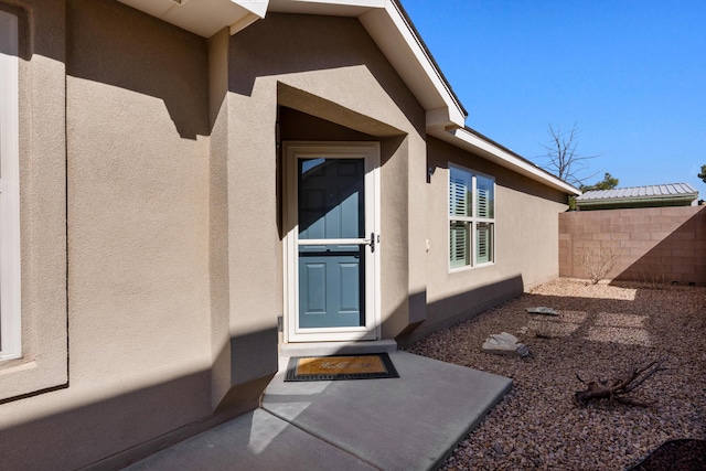 property entrance featuring fence and stucco siding