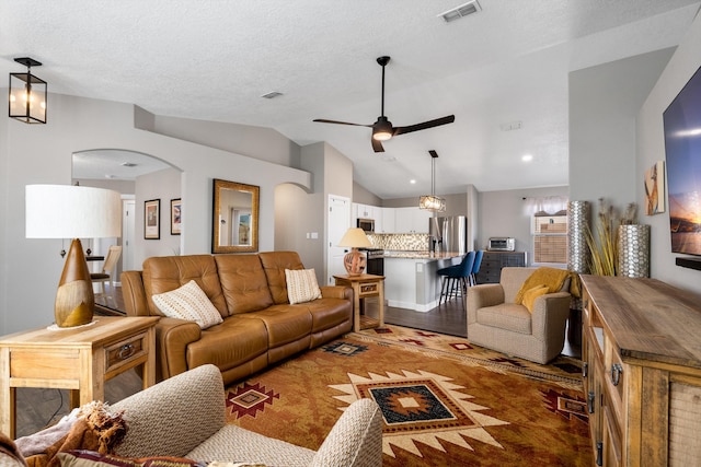 living area featuring visible vents, arched walkways, a ceiling fan, lofted ceiling, and light wood-type flooring