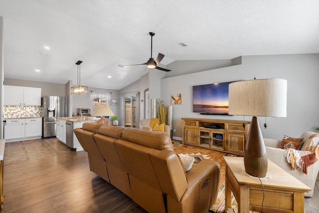 living room with vaulted ceiling, ceiling fan, wood finished floors, and visible vents