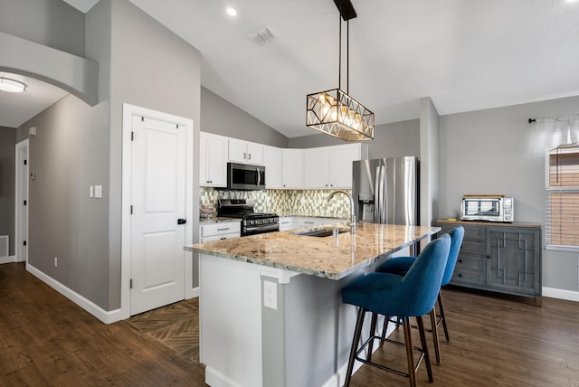 kitchen with arched walkways, stainless steel appliances, a sink, visible vents, and light stone countertops