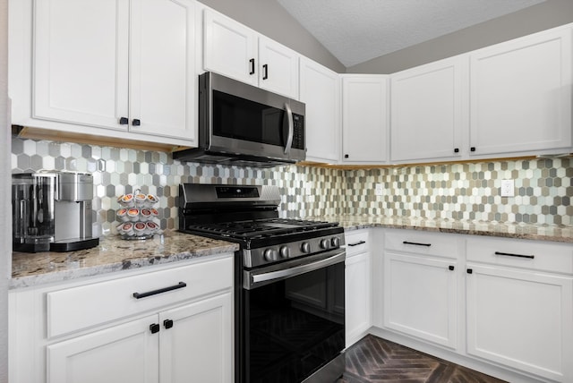 kitchen featuring a textured ceiling, stainless steel appliances, white cabinets, light stone countertops, and tasteful backsplash