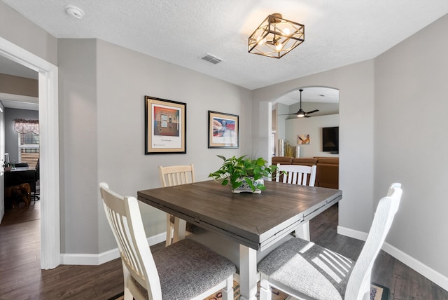 dining space with baseboards, visible vents, arched walkways, wood finished floors, and a textured ceiling