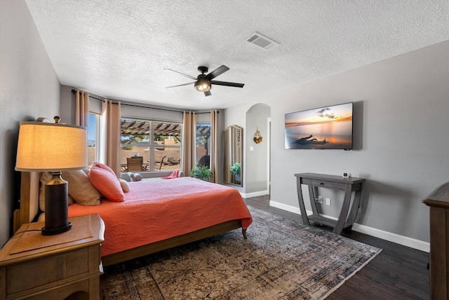 bedroom featuring arched walkways, wood finished floors, visible vents, and baseboards