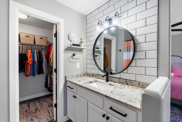 bathroom featuring a spacious closet, vanity, and baseboards