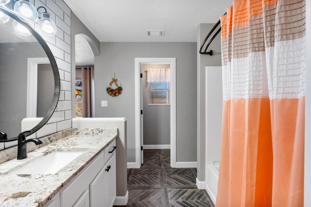 full bathroom with visible vents, baseboards, a shower with curtain, a textured ceiling, and vanity