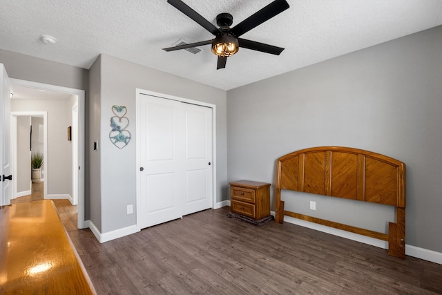 bedroom with a closet, a textured ceiling, baseboards, and wood finished floors