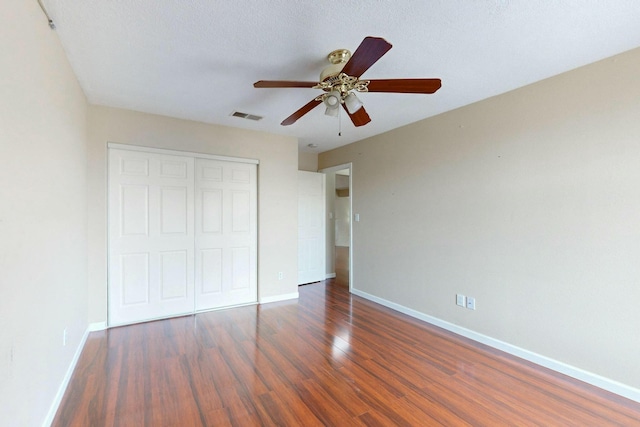 unfurnished bedroom with baseboards, a closet, visible vents, and wood finished floors