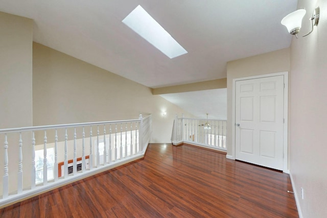 unfurnished room with lofted ceiling with skylight, wood finished floors, and baseboards