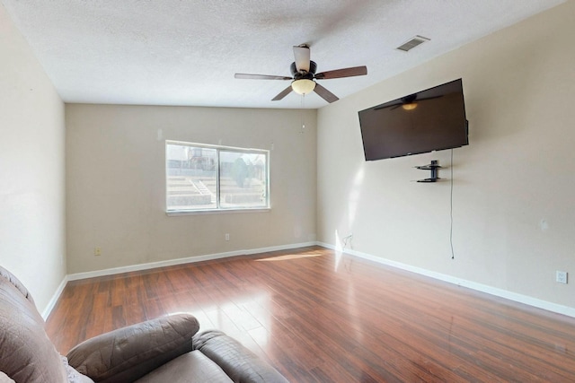 unfurnished living room featuring visible vents, a ceiling fan, a textured ceiling, wood finished floors, and baseboards