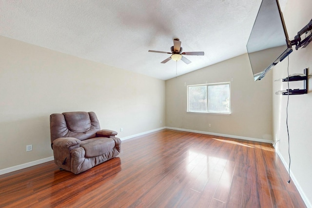 sitting room with lofted ceiling, a textured ceiling, baseboards, and wood finished floors