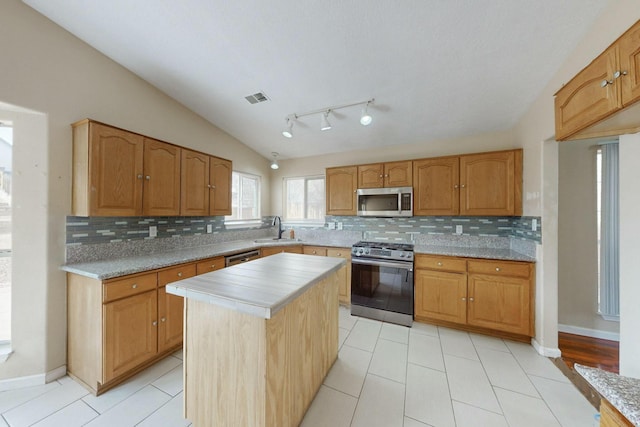 kitchen with stainless steel appliances, lofted ceiling, light countertops, visible vents, and a sink