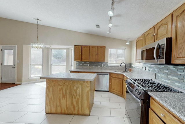 kitchen with a wealth of natural light, vaulted ceiling, stainless steel appliances, and a sink