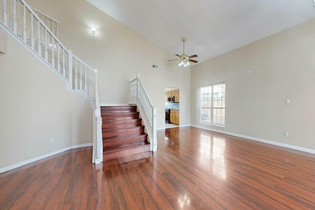 interior space featuring baseboards, visible vents, a ceiling fan, wood finished floors, and high vaulted ceiling