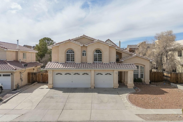 mediterranean / spanish house with a garage, driveway, a tile roof, fence, and stucco siding