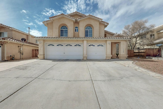 mediterranean / spanish home with an attached garage, fence, a tile roof, concrete driveway, and stucco siding