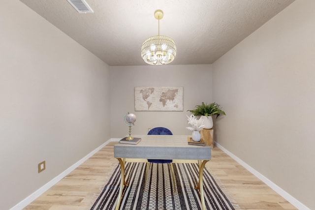 office area with light wood-type flooring, baseboards, visible vents, and a chandelier