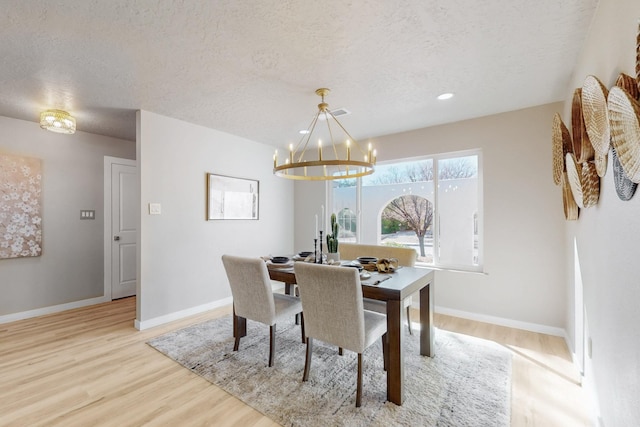 dining space featuring a notable chandelier, wood finished floors, baseboards, and a textured ceiling