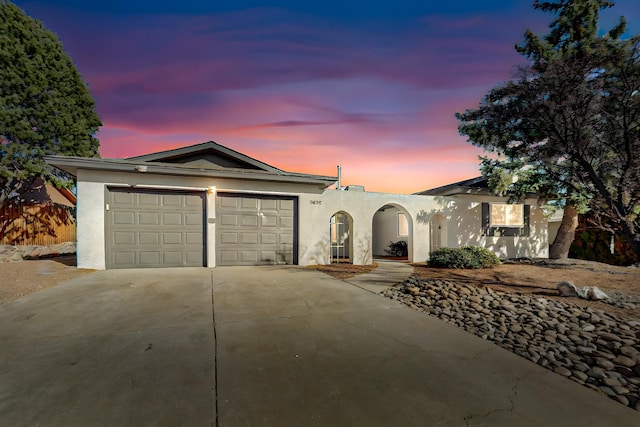 view of front of house featuring stucco siding, a garage, and driveway