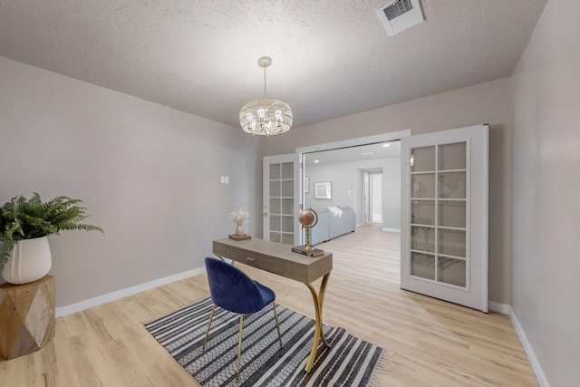 office space featuring an inviting chandelier, light wood-style flooring, baseboards, and visible vents