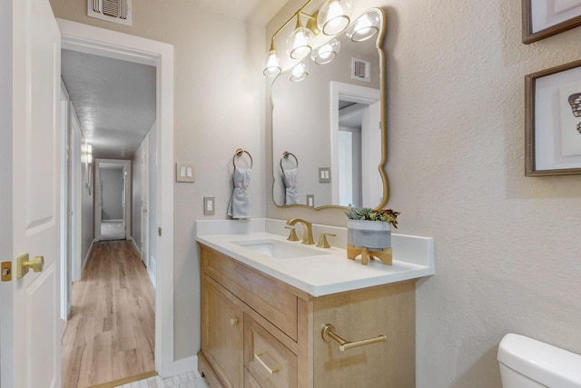 half bathroom with visible vents, baseboards, toilet, and vanity