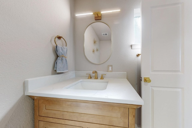 bathroom with visible vents, vanity, and a textured wall