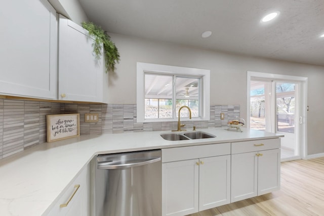 kitchen featuring stainless steel dishwasher, white cabinetry, and a sink