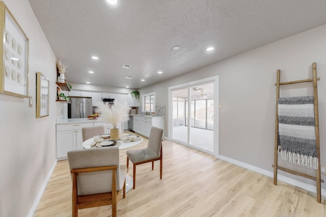 dining area featuring light wood finished floors, recessed lighting, a textured ceiling, and baseboards