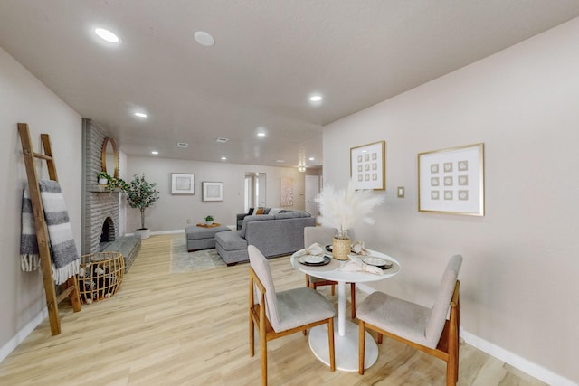 dining room with recessed lighting, light wood-style flooring, a fireplace, and baseboards