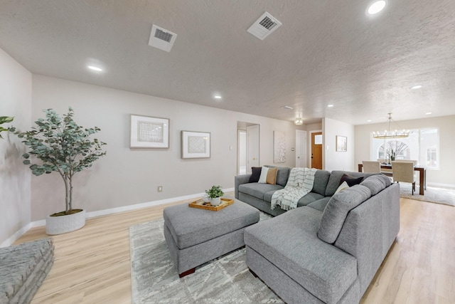 living area with visible vents, light wood-style flooring, and a textured ceiling