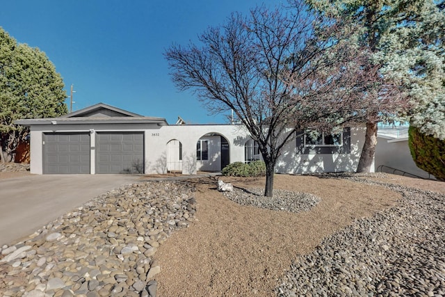 ranch-style house featuring concrete driveway, an attached garage, and stucco siding