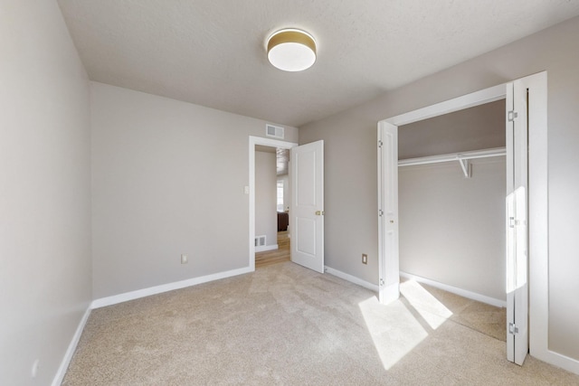 unfurnished bedroom featuring light colored carpet, visible vents, a closet, and baseboards