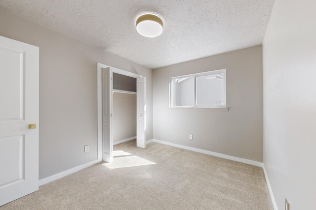 unfurnished bedroom with carpet, baseboards, a closet, and a textured ceiling