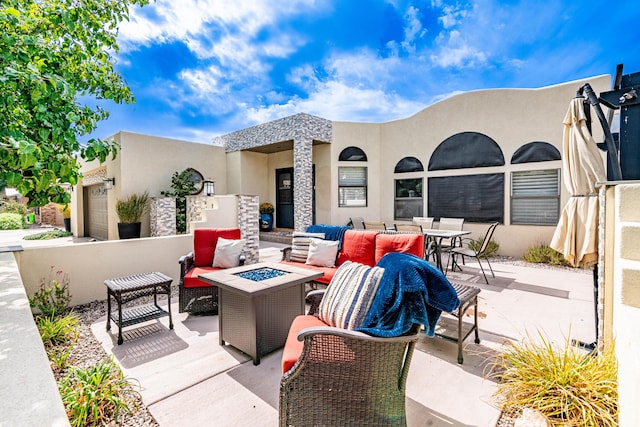 view of patio featuring a garage and an outdoor living space with a fire pit