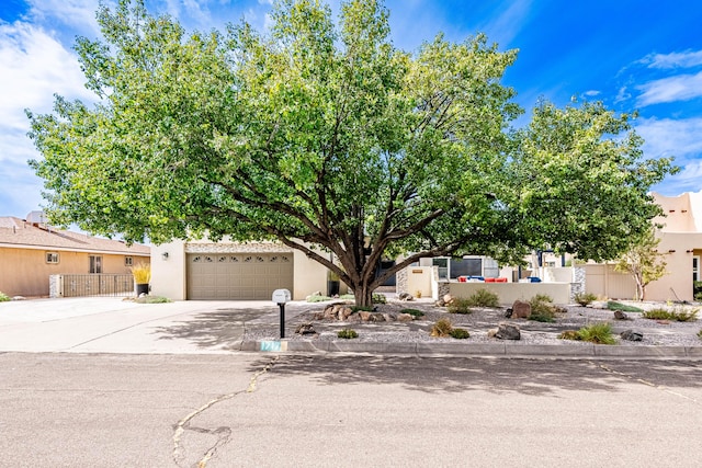 view of front facade with a fenced front yard, stucco siding, concrete driveway, an attached garage, and a gate