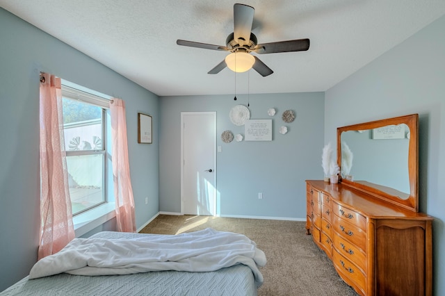 bedroom featuring carpet floors, a textured ceiling, baseboards, and a ceiling fan