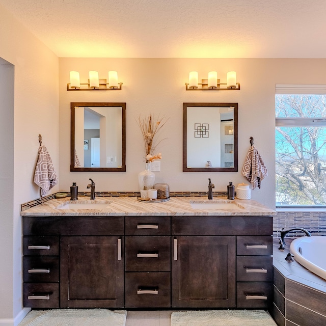 full bath with double vanity, tiled tub, and a sink