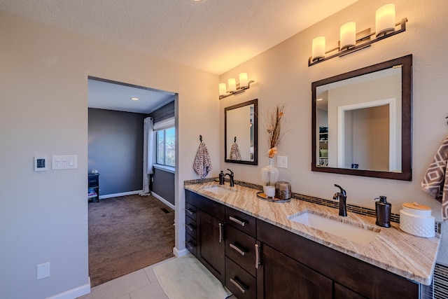 full bath with double vanity, tile patterned flooring, a textured ceiling, and a sink