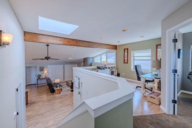 kitchen with open floor plan, light wood finished floors, lofted ceiling with skylight, and baseboards