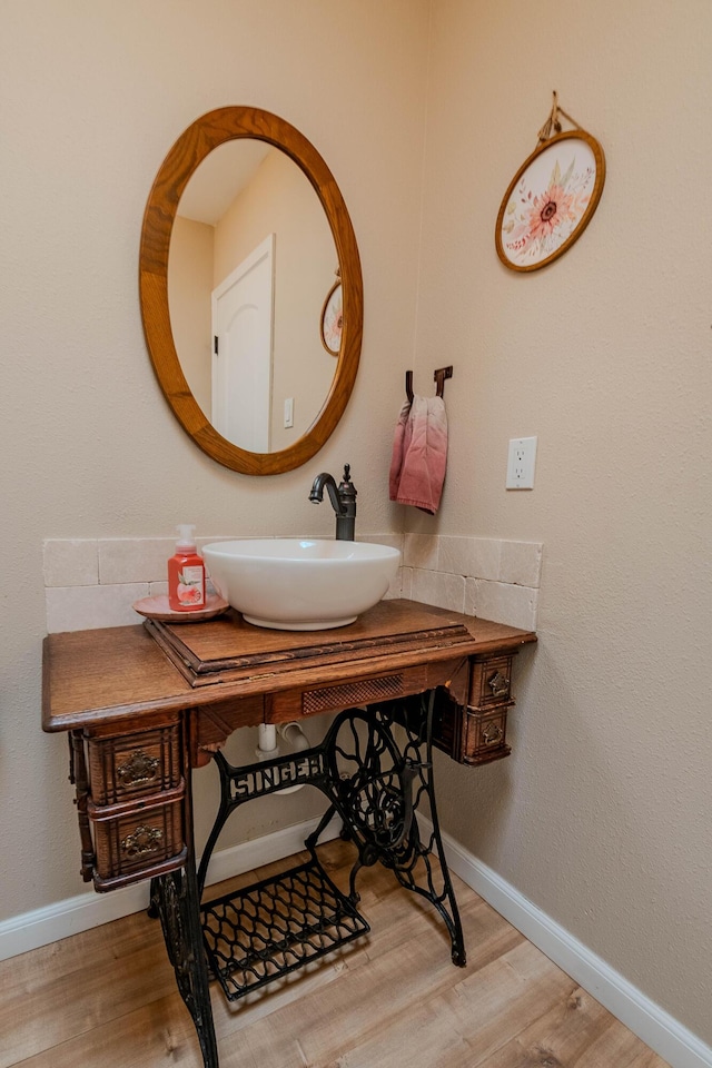 bathroom featuring baseboards, a sink, and wood finished floors