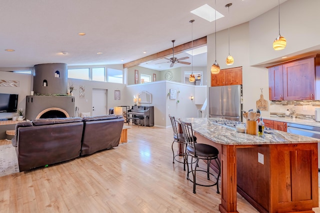 kitchen featuring light wood-style floors, freestanding refrigerator, open floor plan, and a breakfast bar area