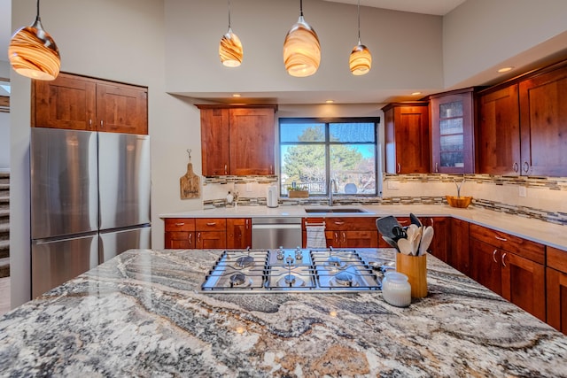 kitchen with decorative backsplash, glass insert cabinets, light stone countertops, stainless steel appliances, and a sink