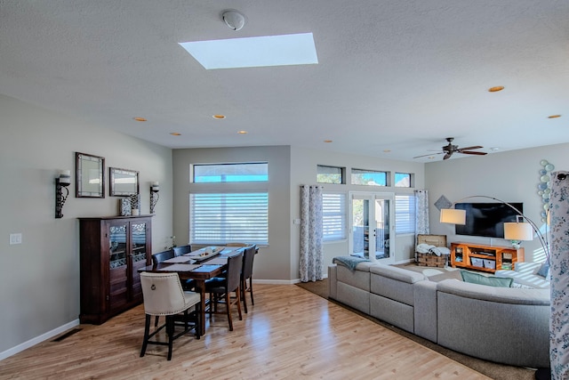 living area featuring light wood-type flooring, visible vents, a textured ceiling, and baseboards