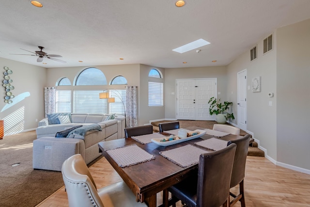 dining room with light wood-style flooring, a skylight, visible vents, and baseboards