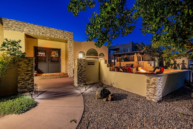 exterior space with stucco siding, stone siding, and area for grilling