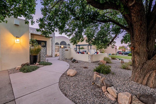 exterior space with stucco siding, stone siding, and a patio