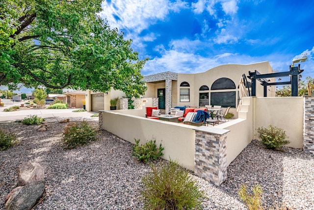 view of front facade with driveway, a garage, a fenced front yard, outdoor lounge area, and stucco siding