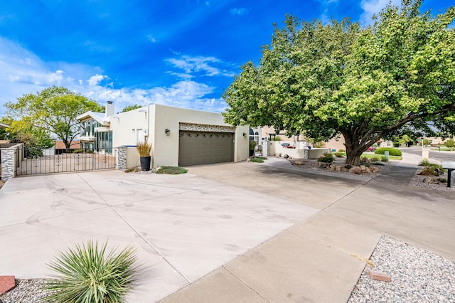 adobe home with driveway, a garage, a gate, fence, and stucco siding