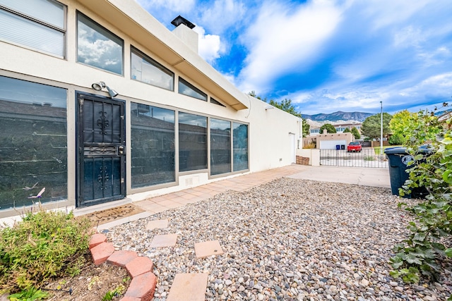 exterior space featuring a chimney, fence, a mountain view, and stucco siding