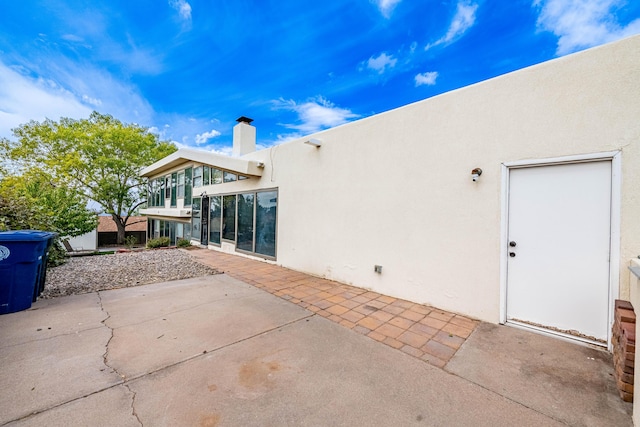 back of property with a patio area, a chimney, and stucco siding